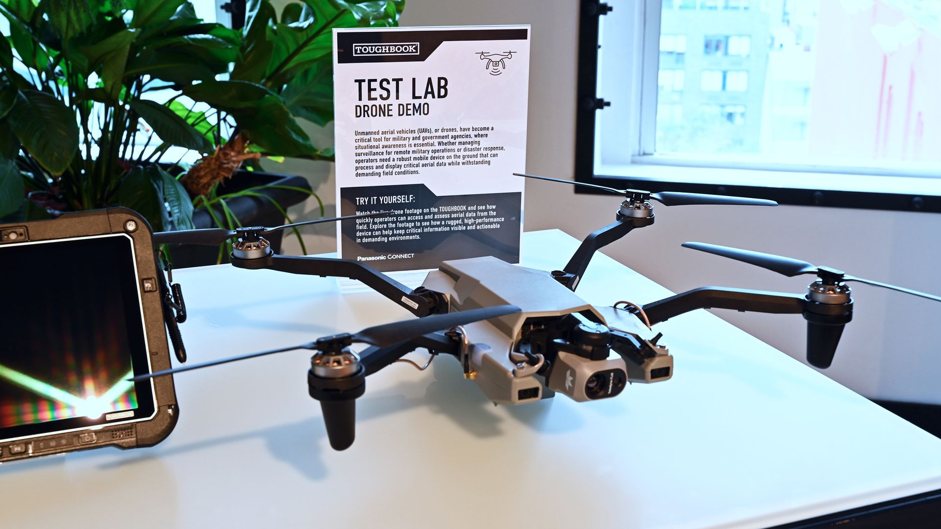 A gray quadcopter drone on a desk next to a 
