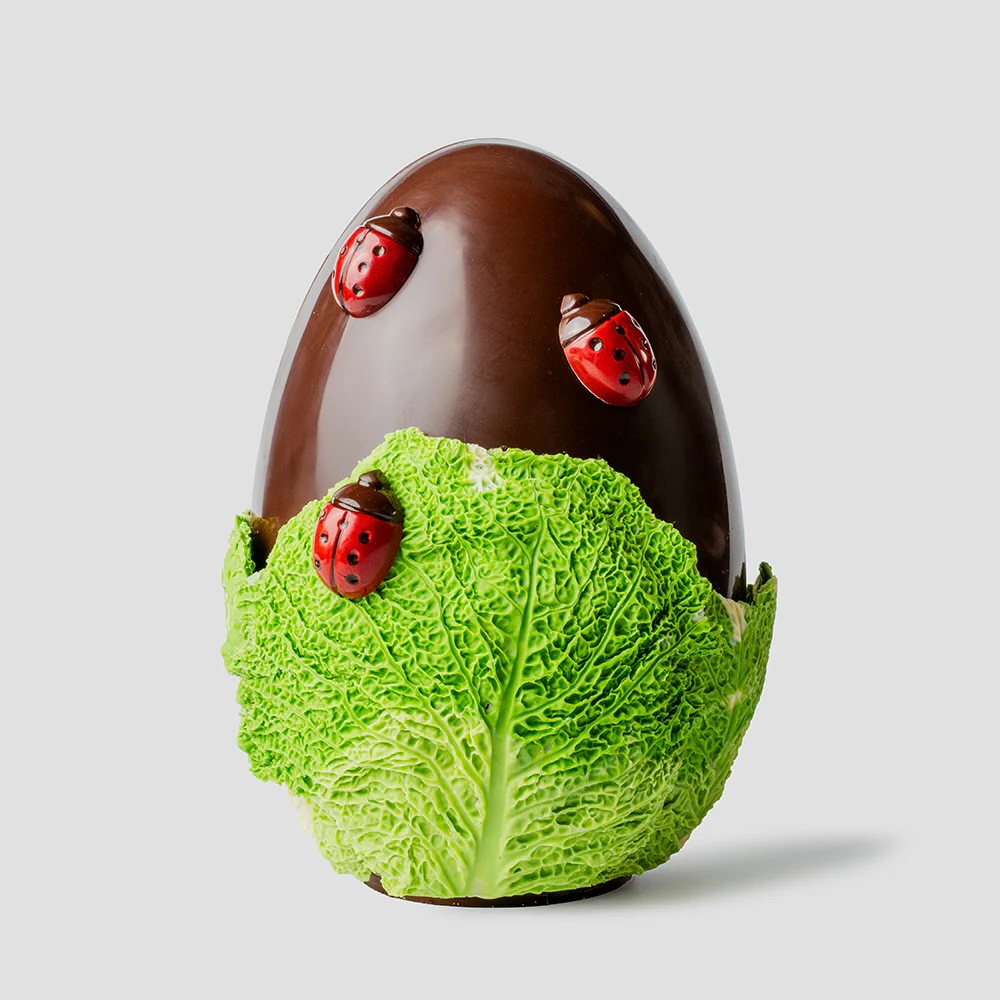 Chocolate Easter egg wrapped in chocolate cabbage leaves and adorned with plump chocolate ladybirds