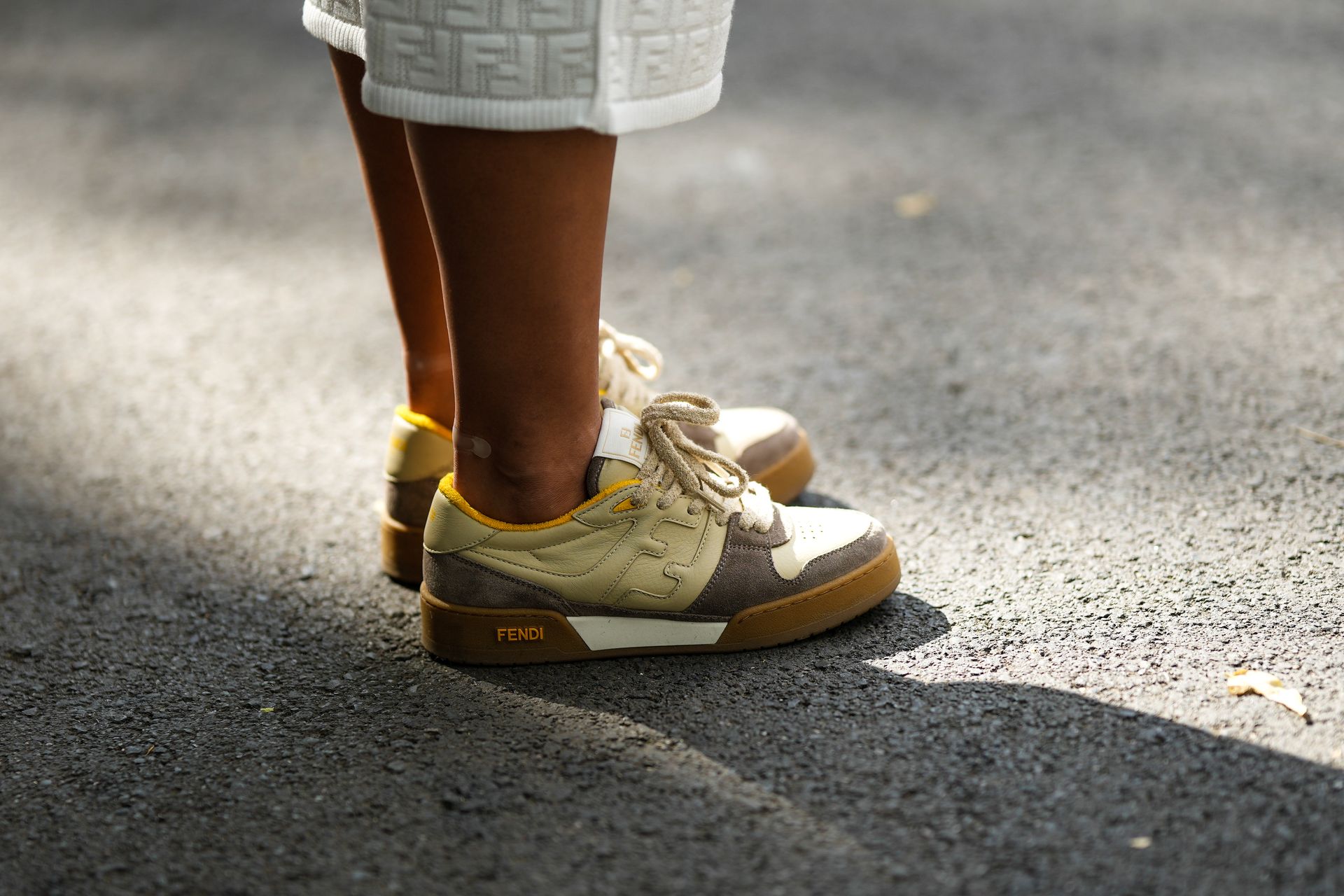 woman in white and brown Fendi sneakers