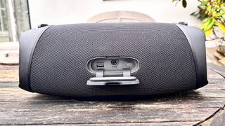 LG XBoom Go XG8T wireless speaker on wooden garden table showing connections