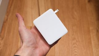 Belkin BoostCharge Pro 140W 4-Port GaN Wall Charger held in a hand above a wooden floor