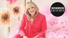 Sara Davies in a pink outfit, surrounded by pastel flowers smiling at the camera 