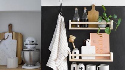 Ikea spice racks used as wall shelves on a black wall in a kitchen