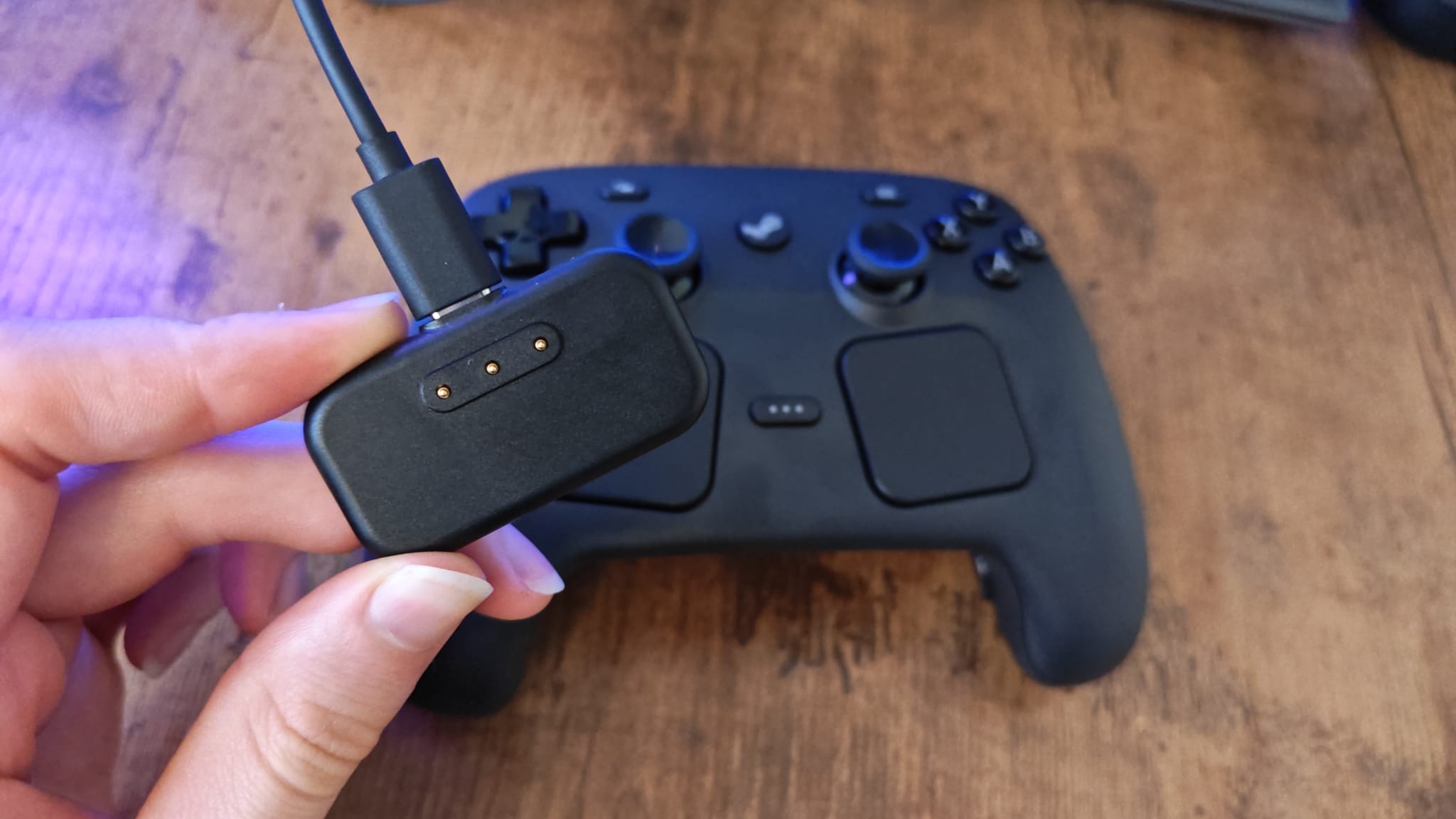 A reviewer holding the Steam Controller puck in front of the gamepad
