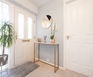 white uPVC front door with glazed top panels in door and to side, in grey painted hallway with marble and gold console table, orchid and plant in grey and white pot