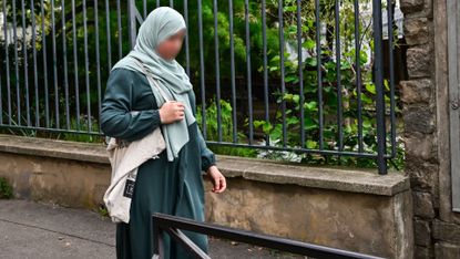 Woman wearing an abaya robe and headscarf outside school in France