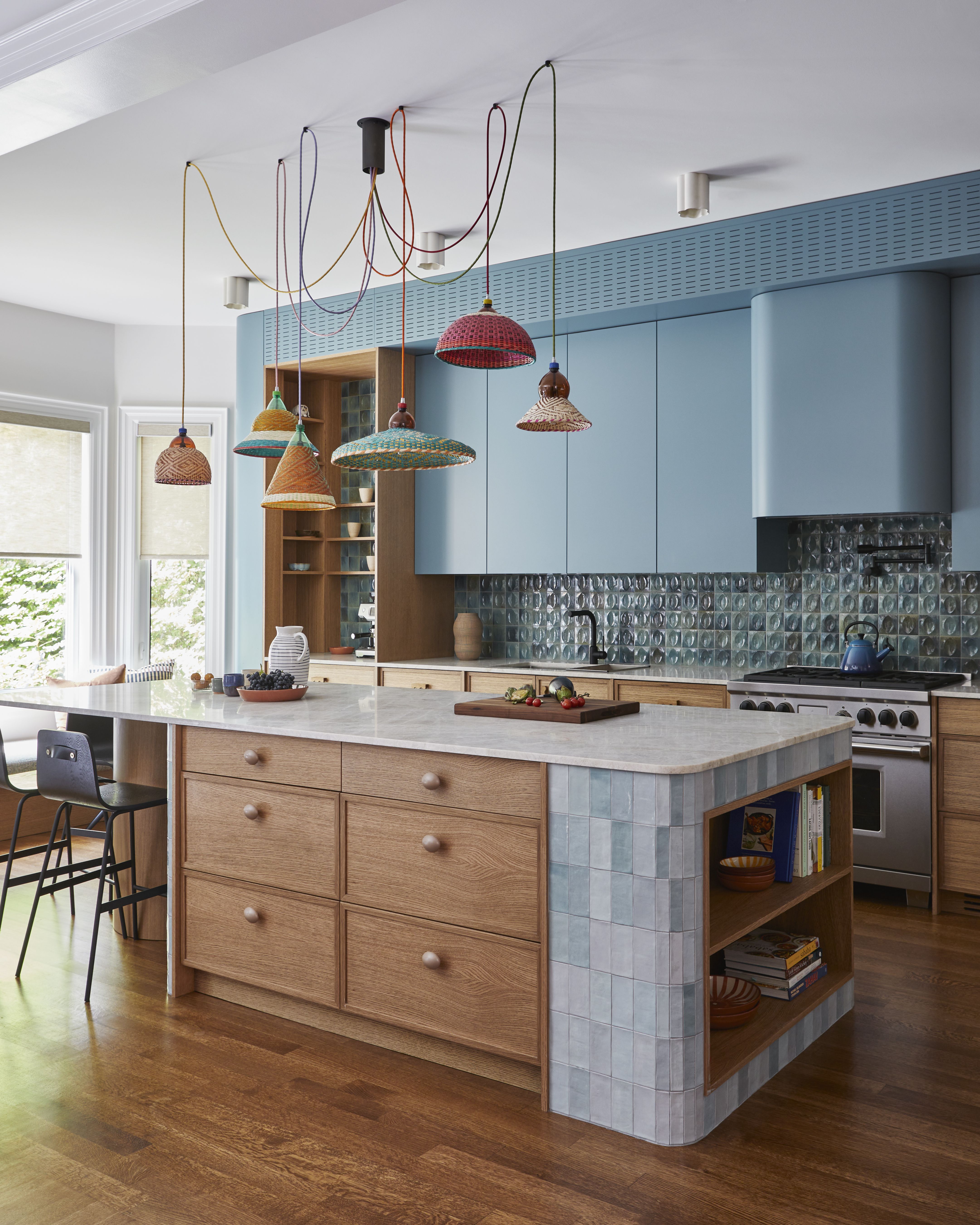 a blue kitchen with a wood and tile island and colorful lighting 