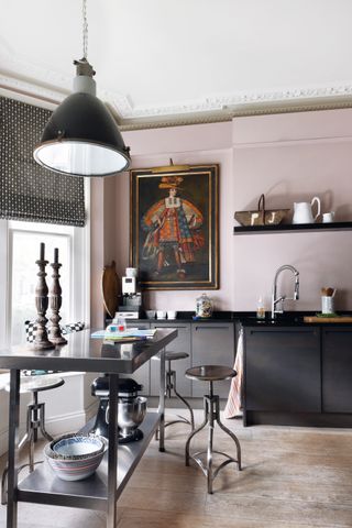Pink and black kitchen with rolling island and large artwork