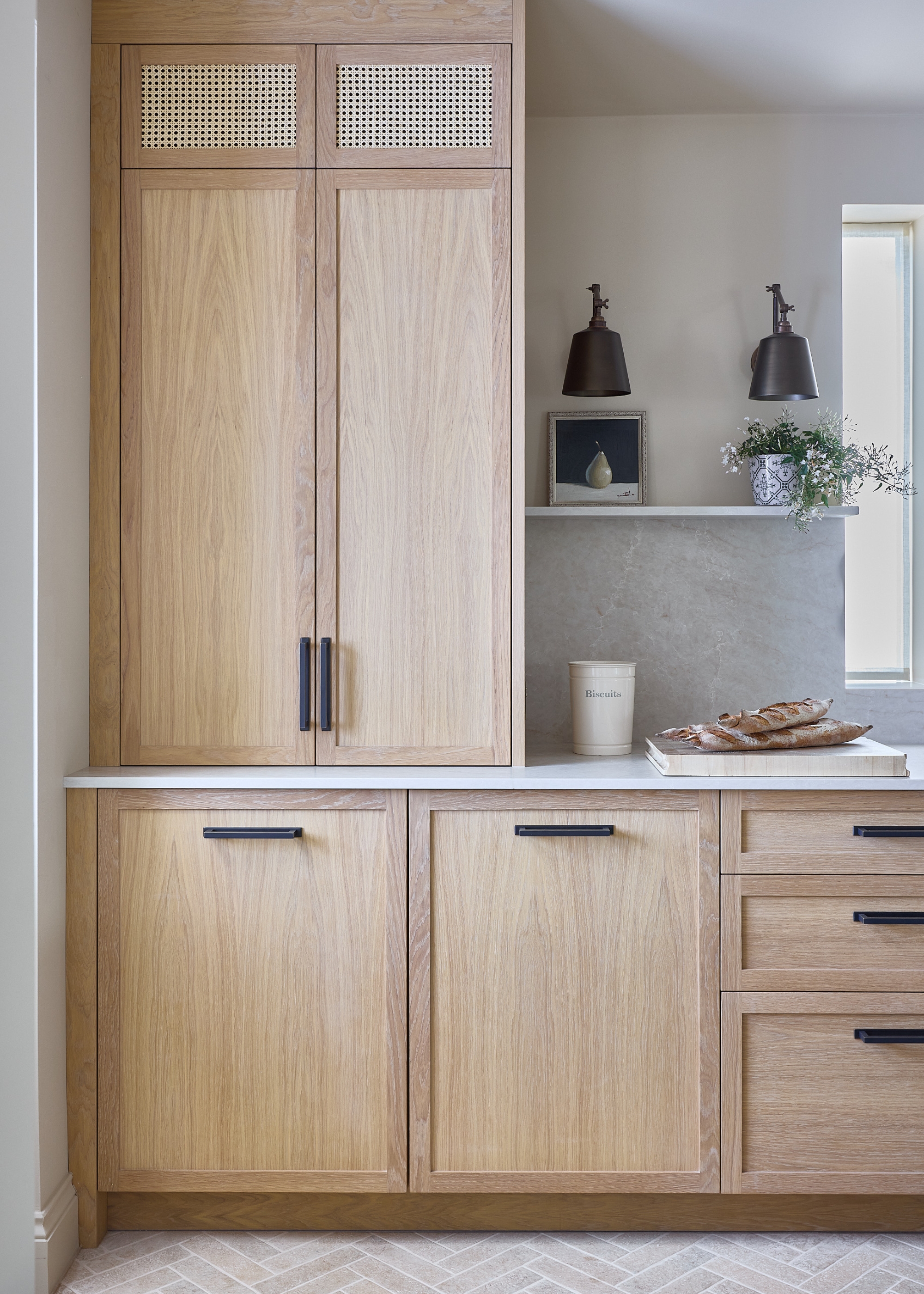 A light wood modern kitchen with black hardware and slate grey wall lights