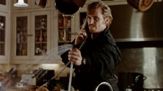 Denis Leary looking angry while on the phone and spraying water from a sink in The Ref