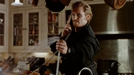 Denis Leary looking angry while on the phone and spraying water from a sink in The Ref