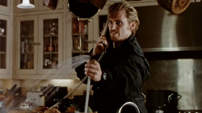 Denis Leary looking angry while on the phone and spraying water from a sink in The Ref