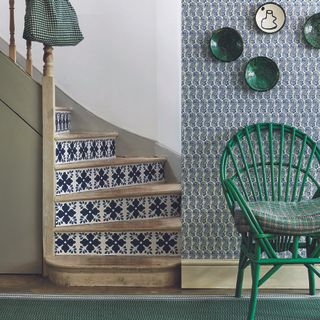 Green hallway with tiled staircase and green chair next to stairs.