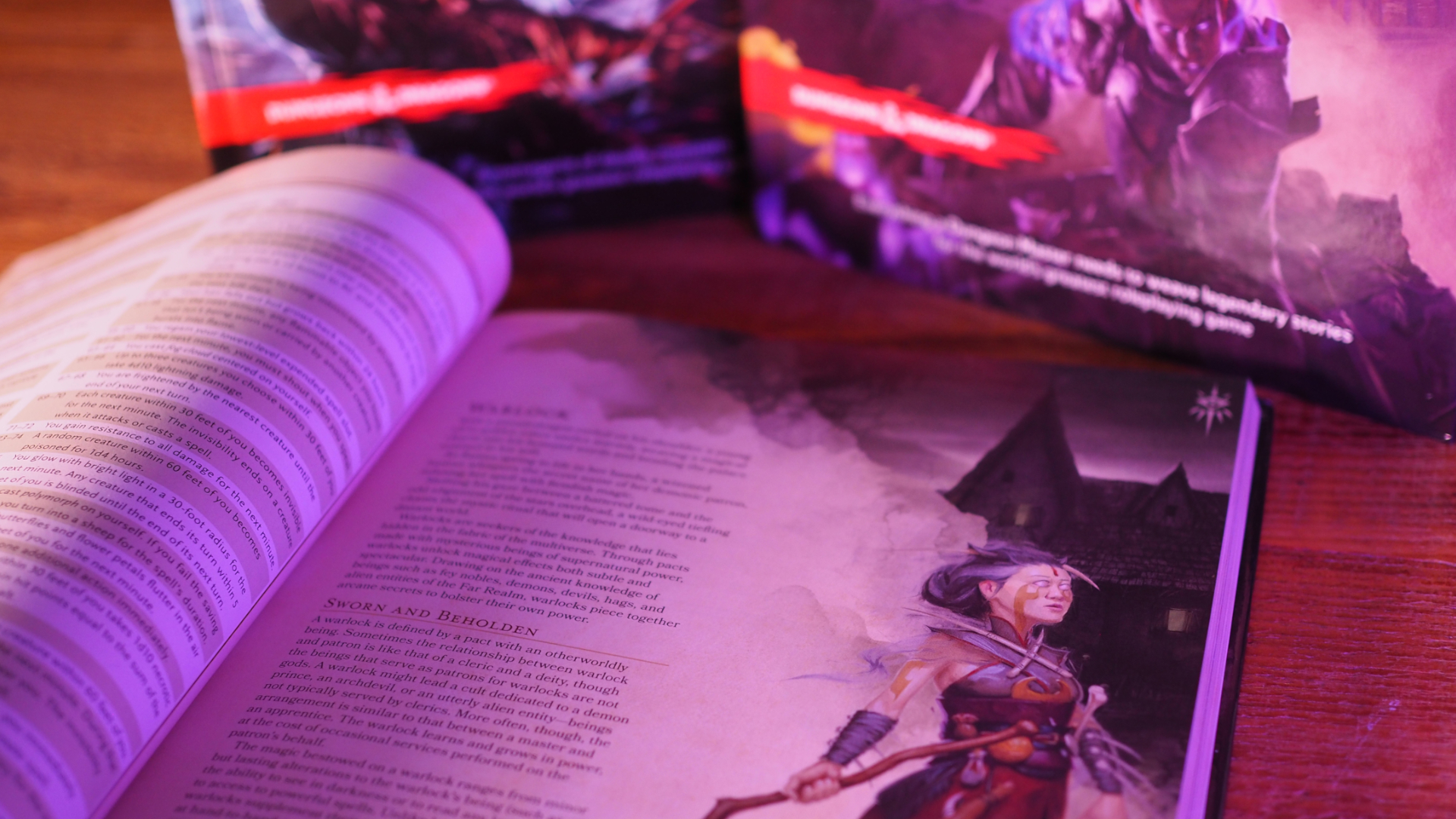 An open player's handbook with the Warlock page lies on a wooden table, behind it are a monster manual and a Dungeon Master's Guide