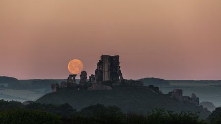 Moonset over the ruins of Corfe Castle in Dorset, UK.