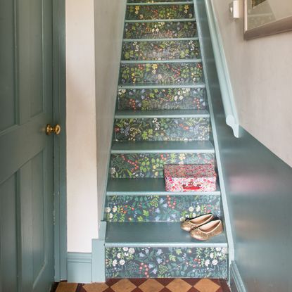 Floral wallpaper-covered teal stairs in a hallway with matching doors