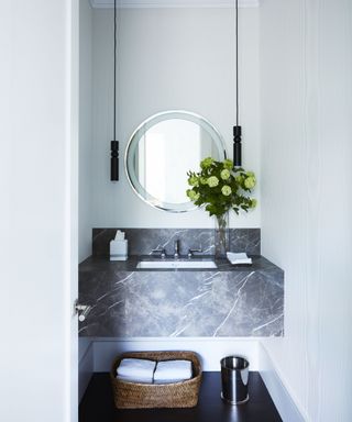narrow bathroom ideas, small bathroom with built in marble sink, round mirror, pair of pendant lights, basket