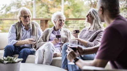 Two retired couples drink wine and laugh together.