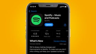 An iPhone on an orange background showing the Spotify app being updated