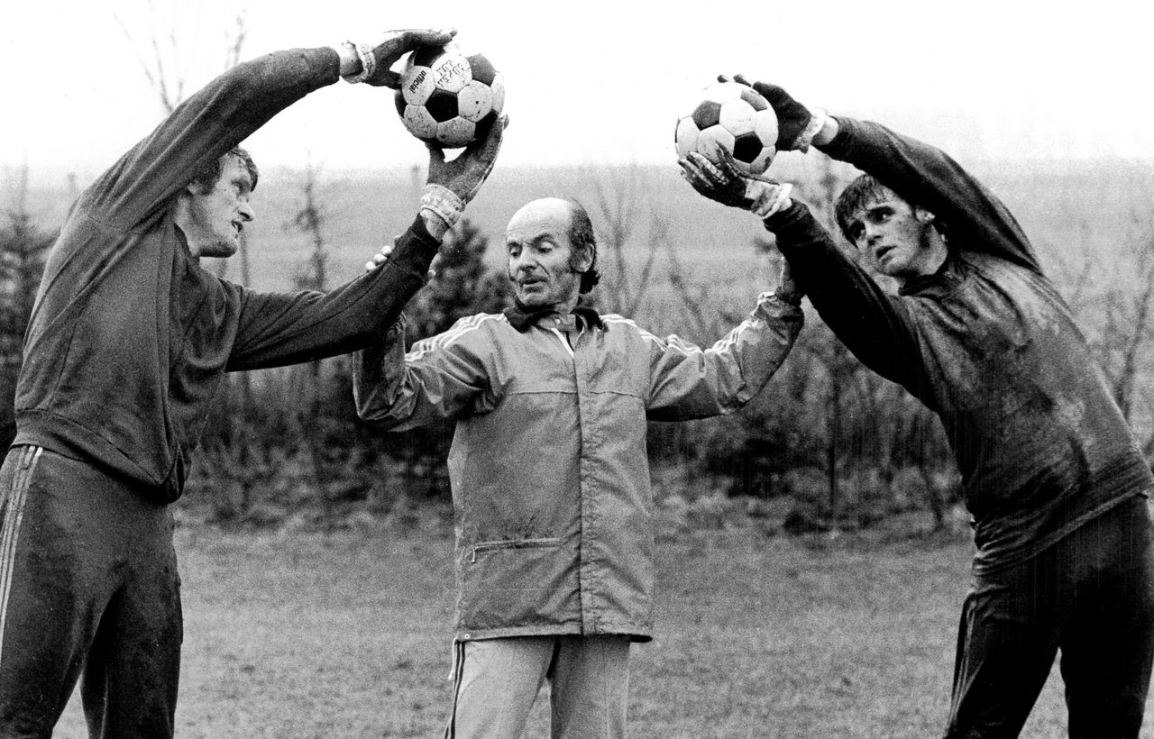 Bayern Munich goalkeepers Sepp Maier and Hugo Robl stretch either side of manager Dettmar Cramer during a training session in 1975