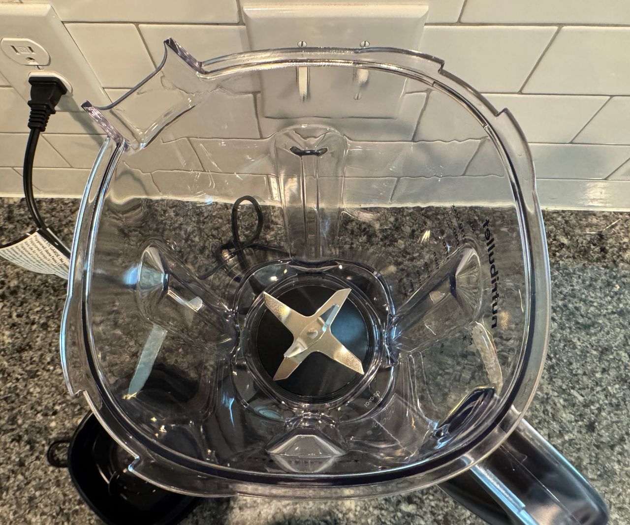 The inside of the clear plastic pitcher of a blender with stainless steel blades.