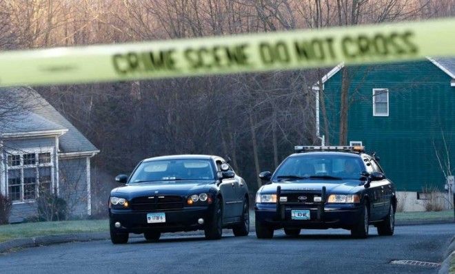 Newtown police officers watch over a blocked-off section of Yogananda Street on Saturday morning, where the the mother of Adam Lanza, the alleged shooter, was killed at her home on Friday.