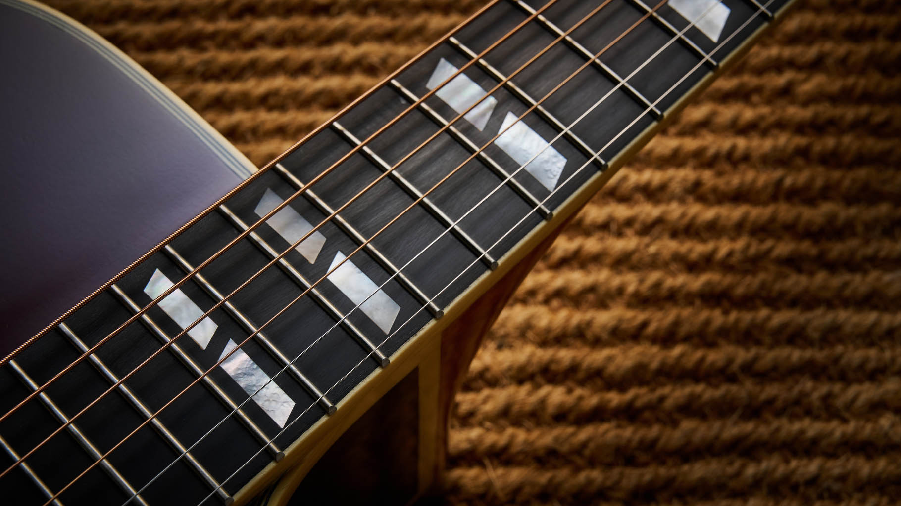 The Epiphone Inspired by Gibson Custom Hummingbird photographed in all its glory, in close-up and against a wheat-coloured rug.