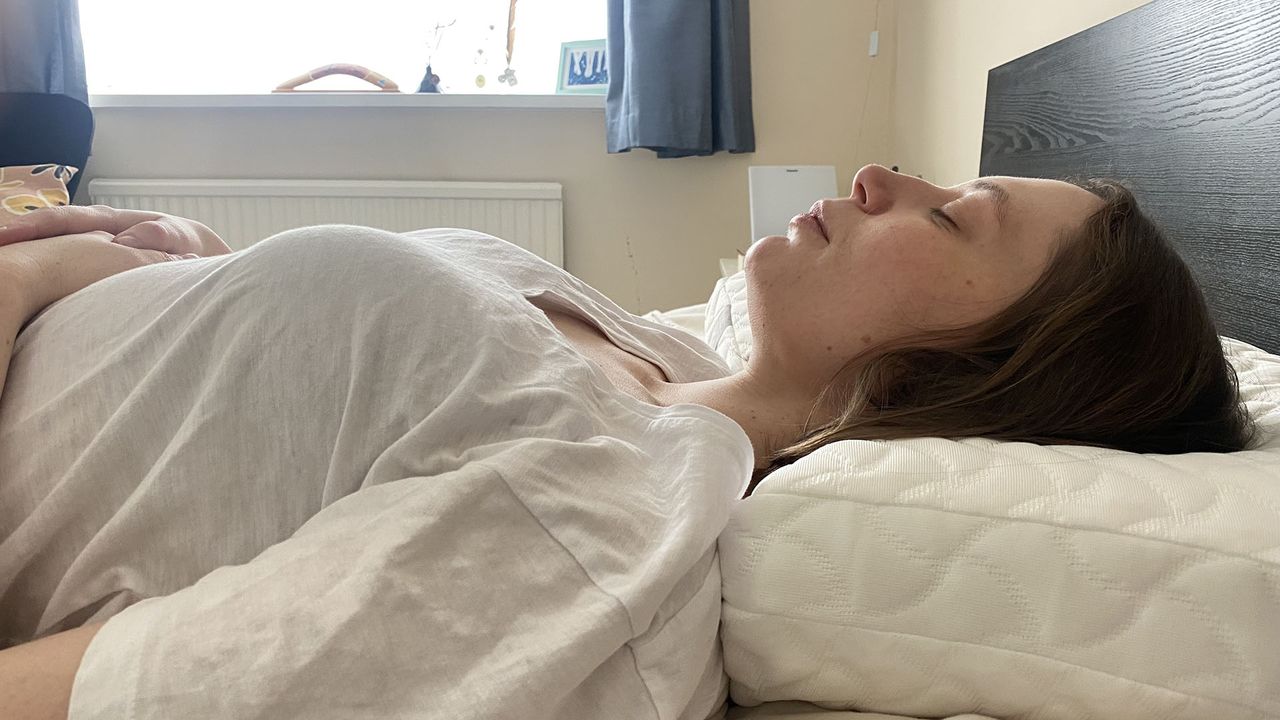 A woman lies on her back with her head resting on the Tempur-Pedic Tempur-Cloud Pillow.