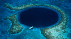 Belize lighthouse reef with a boat moored at Blue Hole - aerial view
