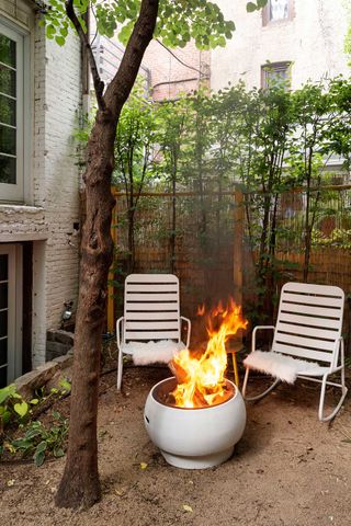 small garden with white fire pit and modern white garden chairs