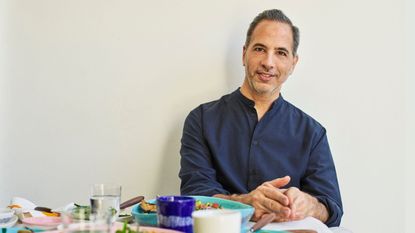 Yotam Ottolenghi on a cream background with his serax dishes in front of him