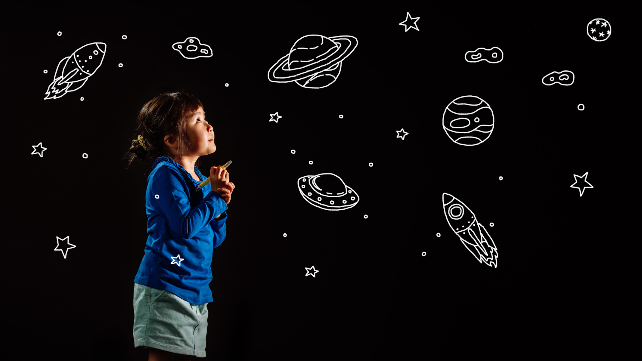 small child drawing astronomy pictures on a black background