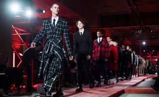 A group of male models on the cat walk modelling clothing by Alexander McQueen.