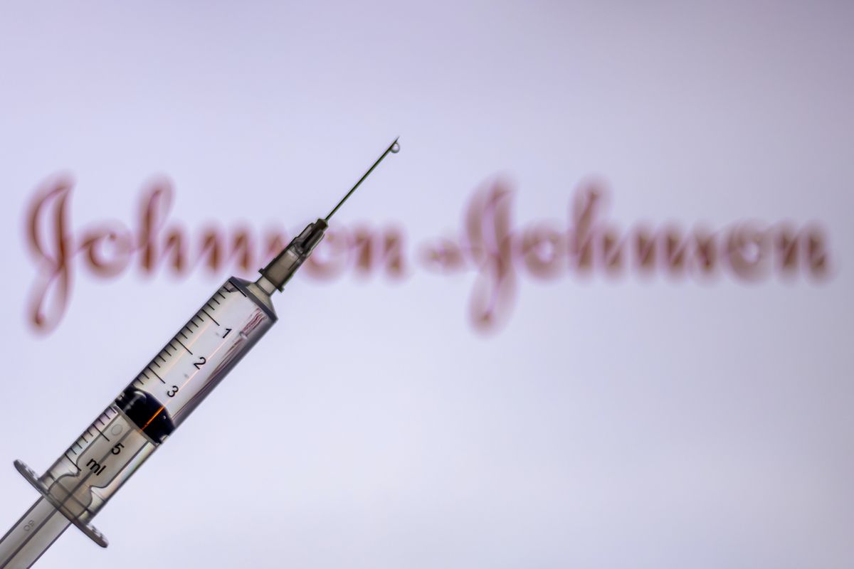 A syringe in front of a Johnson&amp;Johnson logo.