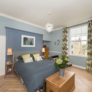 bedroom with blue wall grey bed with cushions wooden flooring