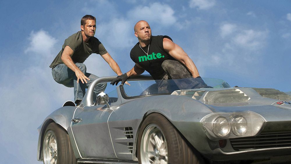 Paul Walker and Vin Diesel standing on top of moving car