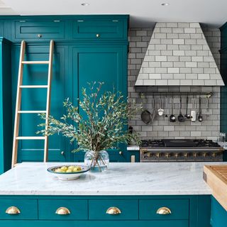 Turquoise kitchen with grey cooker hood and splashback and brass details