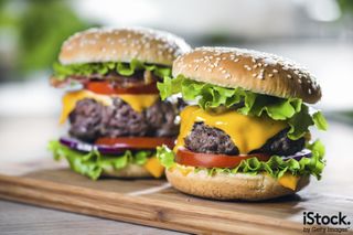 Two homemade cheeseburgers on oak chopping board by Krystian Nawrocki