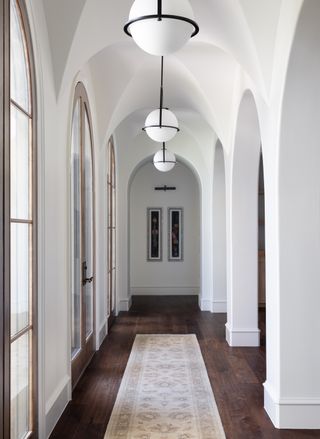 hallway with vaulted ceilings in white, dark floors and glazed doors