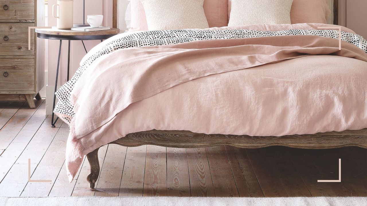 Pale pink bedroom with a vintage-style wooden bed with exposed original flooring to show affordable floorboard insulation recommendation