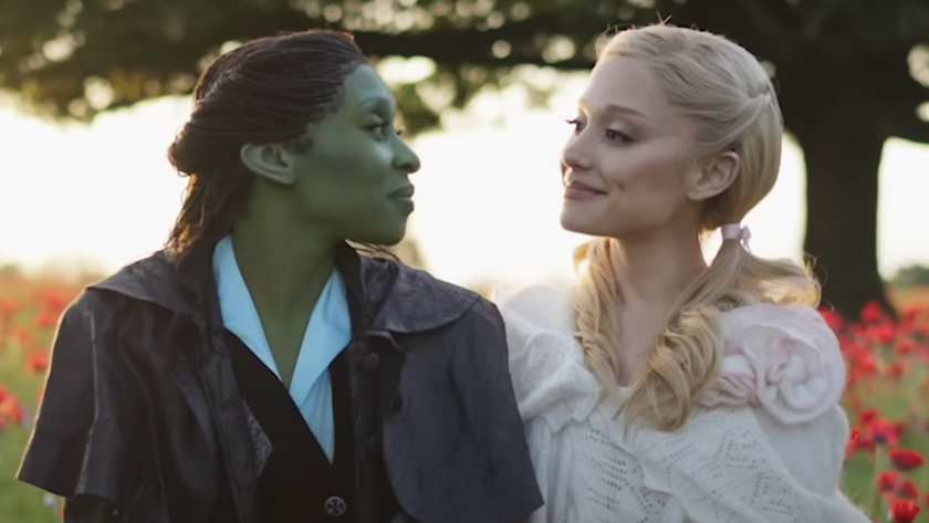 Cynthia Erivo&#039;s Elphaba and Ariana Grande&#039;s Glinda looking at each other smiling on the set of Wicked: For Good with poppy fields behind them