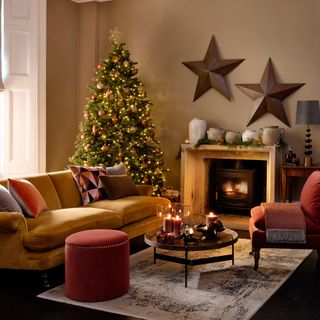 Living room with a large Christmas tree decorated with metallic decorations and two large stars hanging on the wall