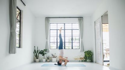 TikTok headstand challenge woman in yoga studio on mat standing on her head
