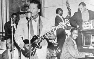 Chuck Berry (foreground) performs onstage with his band in 1957