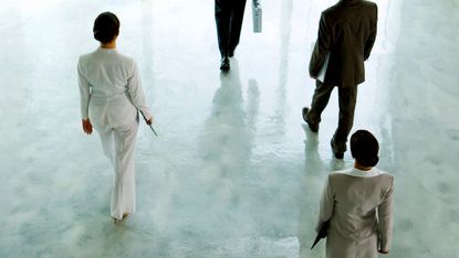 Executives shown from above walking across a hallway
