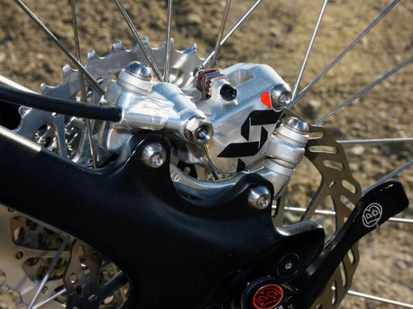 Shiny titanium bolts and a polished adapter hold the Avid XX rear caliper in place.