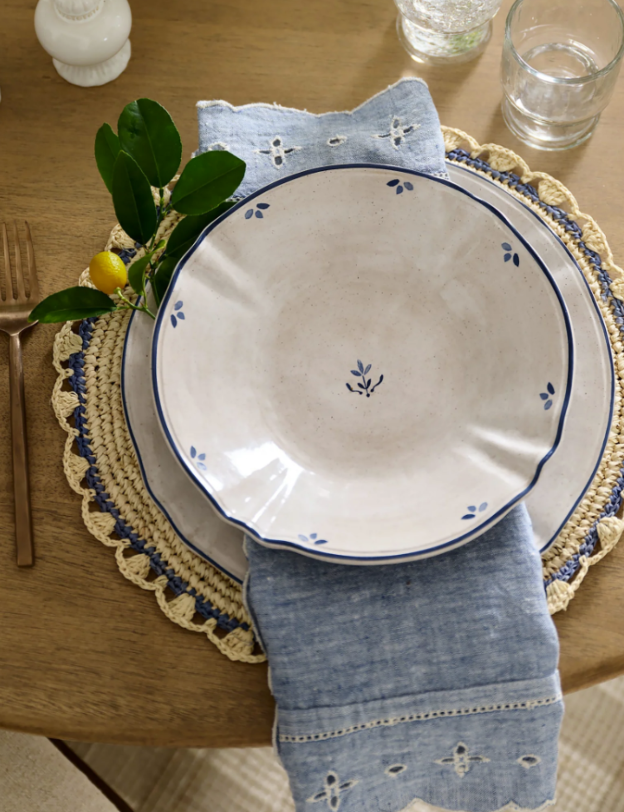 Vintage-inspired table setting featuring a woven placemat, eyelit lace border napkin, and Danish dinner plates.