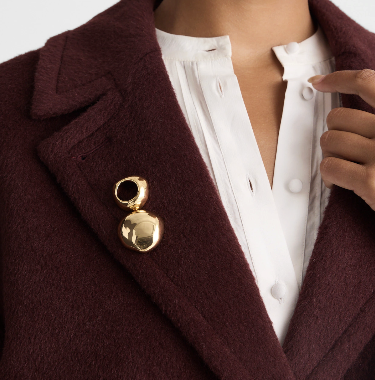 gold brooch on burgundy wool coat