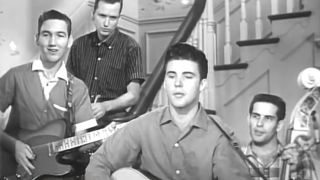 Ricky Nelson playing acoustic guitar with a band on The Adventures of Ozzie and Harriett