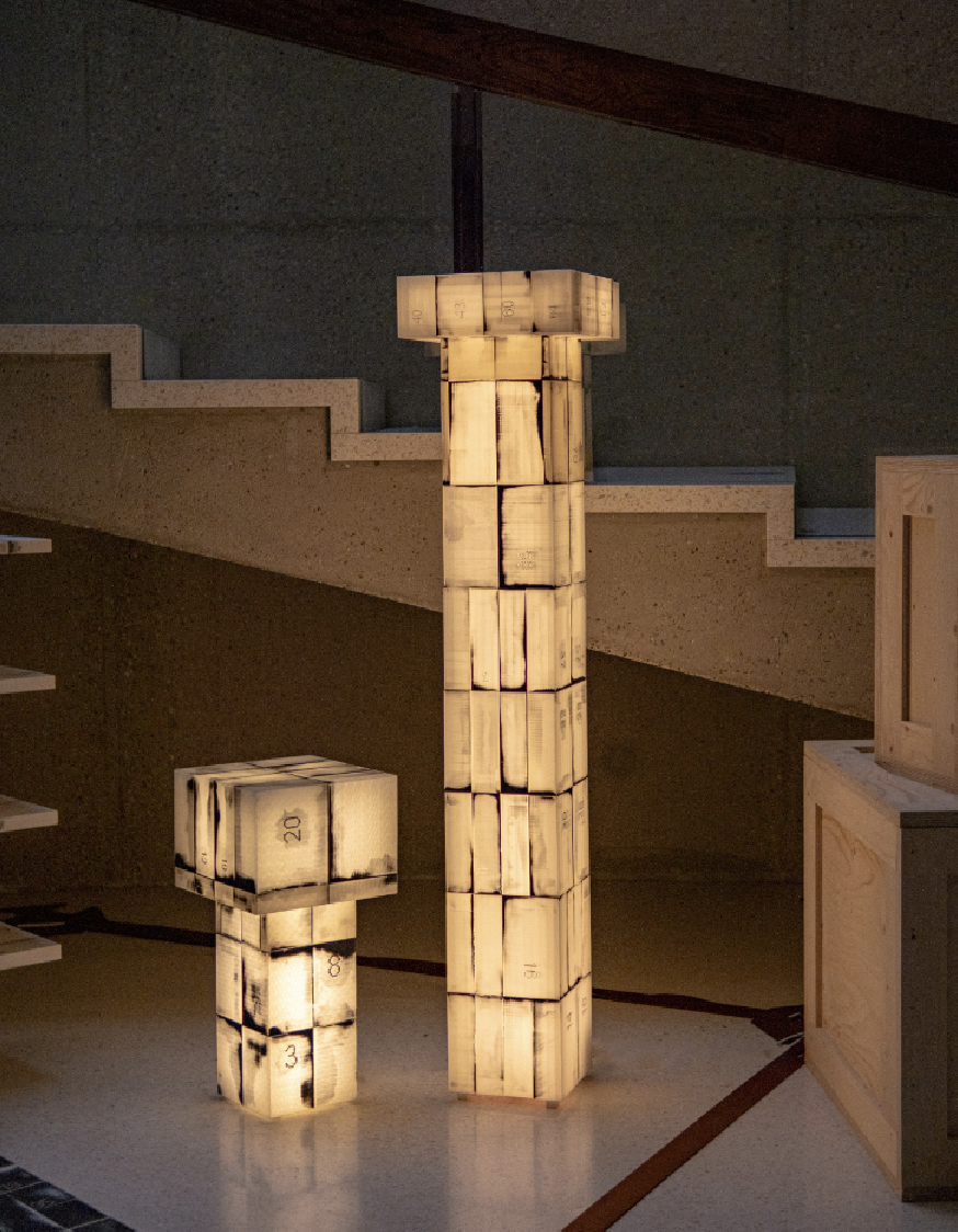 Standing lamps made of multiple, number-printed facets, presented in a modernist salon.